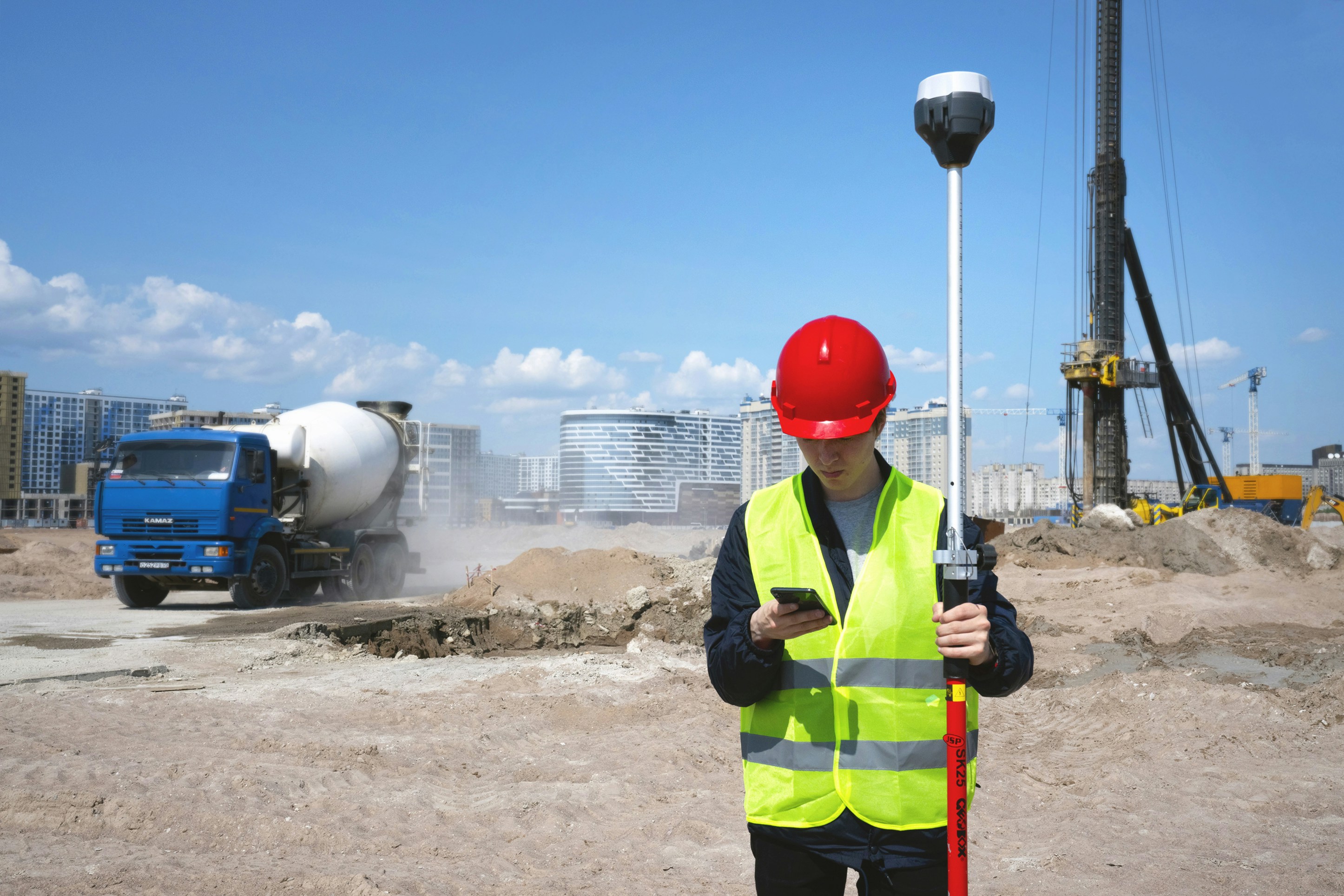 Specialist measuring with a GNSS receiver pole on a construction site